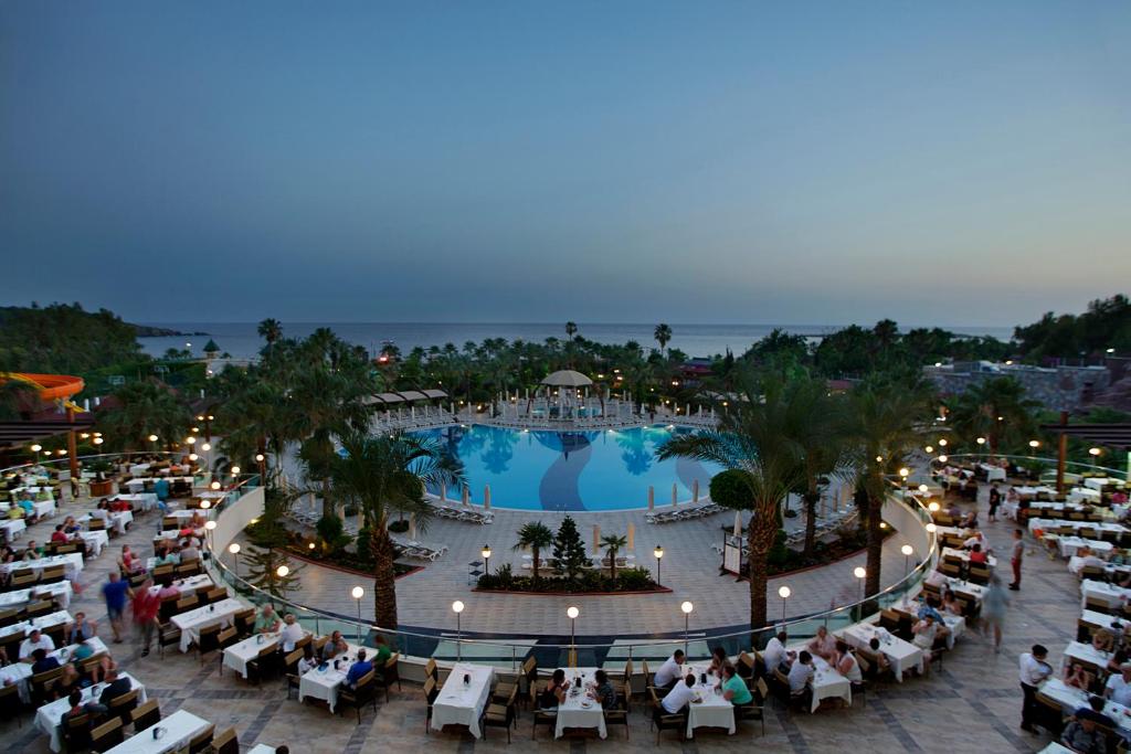 Saphir Resort & Spa baseins ar restorānu piekrastē, saulrieta gaismā