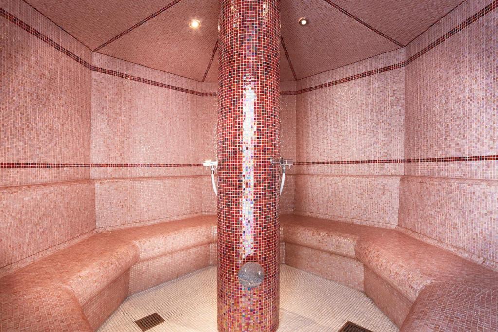 Siltā tvaika pirts ar rozā mozaīkas flīzēm un ērtām sēdvietām, radot relaksējošu atmosfēru. Ideāla vieta atpūtai un atjaunošanai.