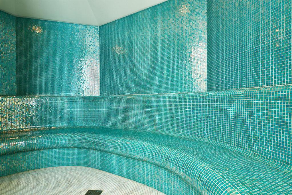 Tirkīza krāsas mozaīkas telpa ar sēdvietām un gludām sienām, radot relaksējošu atmosfēru. Ideāla vieta, lai atpūstos un izbaudītu mieru.