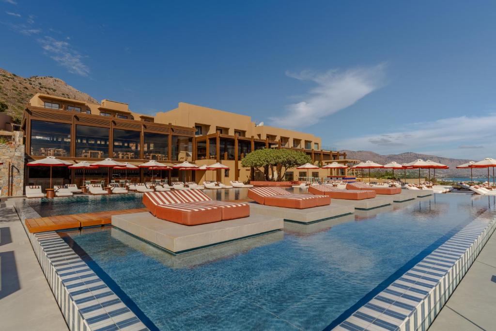 INNSiDE by Meliá Elounda āra baseins ar peldošām atpūtas lāvām un skatu uz kalniem.