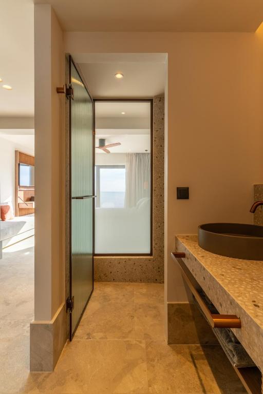 Mūsdienīga vannas istaba ar akmens izlietni un skatu uz jūru INNSiDE by Meliá Elounda numurā.