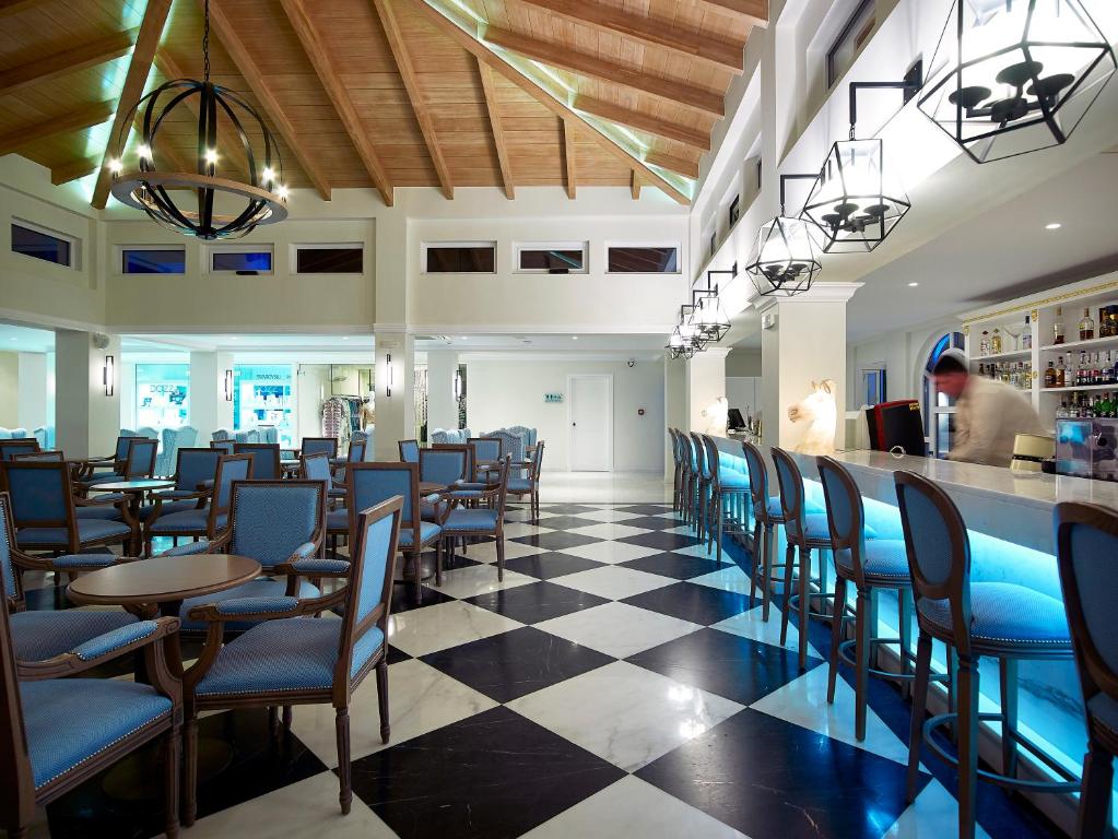 Moderns bārs ar elegantu dizainu, koka griestiem un melnbaltu grīdu. Telpa ir gaiša ar stilīgām mēbelēm un barošanas letēm, radot patīkamu atmosfēru.