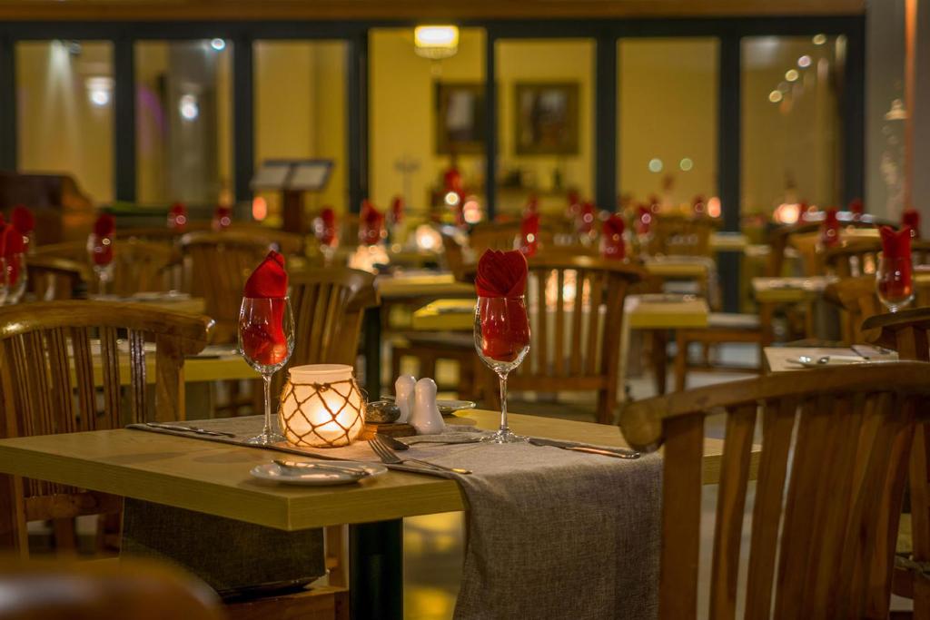 Elegants restorāns ar siltu apgaismojumu, koka mēbelēm un galdiem, kas dekorēti ar sarkaniem salvetēm un glāzēm. Ideāla vieta romantiskām vakariņām vai svinībām.