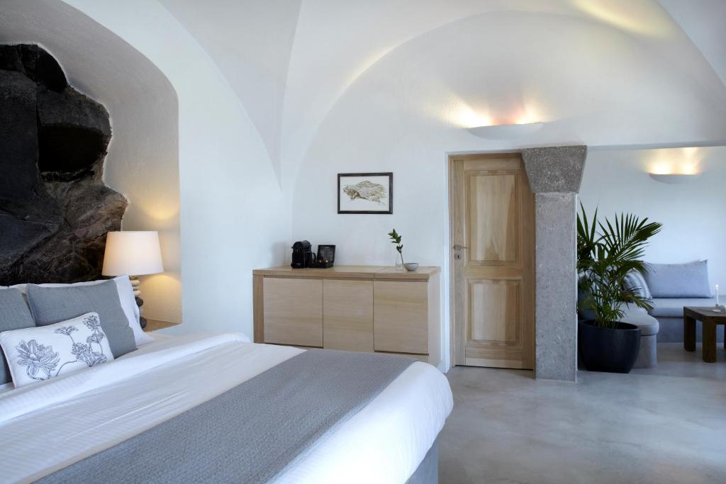 Mūsdienīgs guļamistabas interjers ar akmens sienu, gultu un koka mēbelēm, kas radījušas relaksējošu atmosfēru. Telpā ir iekārtoti augi un mīkstās mēbeles, kas papildina dizainu.