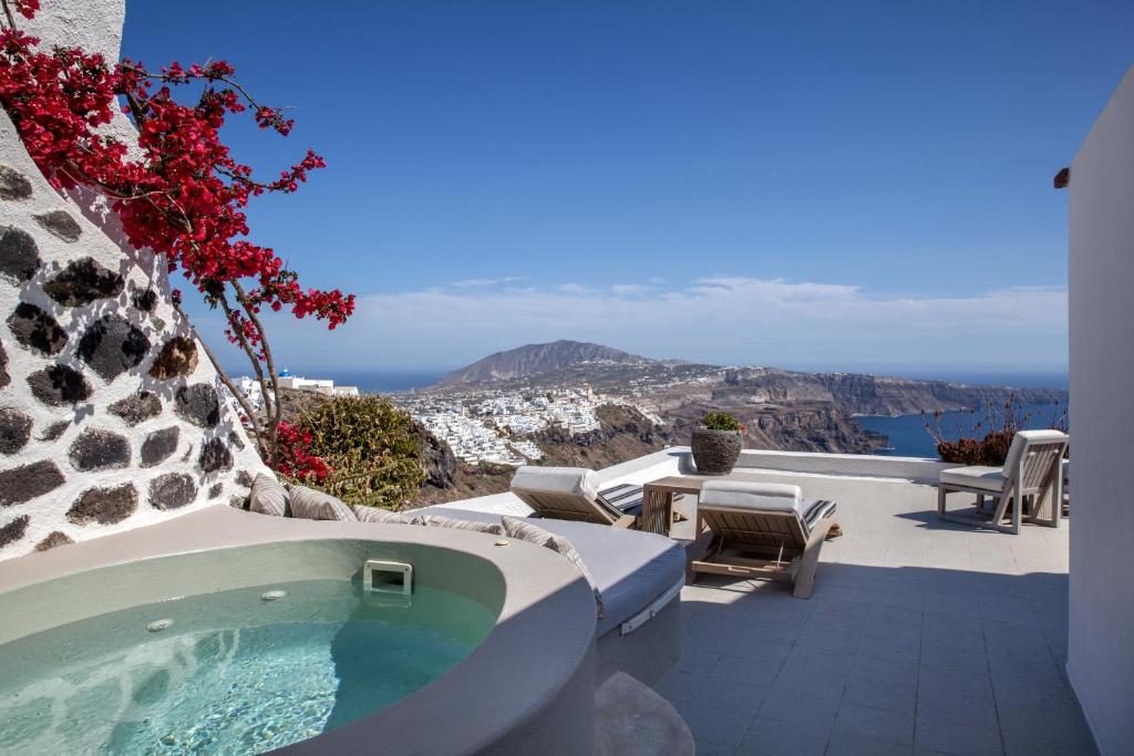 Relaksējoša terase ar burbuļvannu un skatu uz Santorini kalniem un jūru, dekorēta ar ziediem un modernas mēbeles. Ideāla vieta atpūtai un dabas baudīšanai.