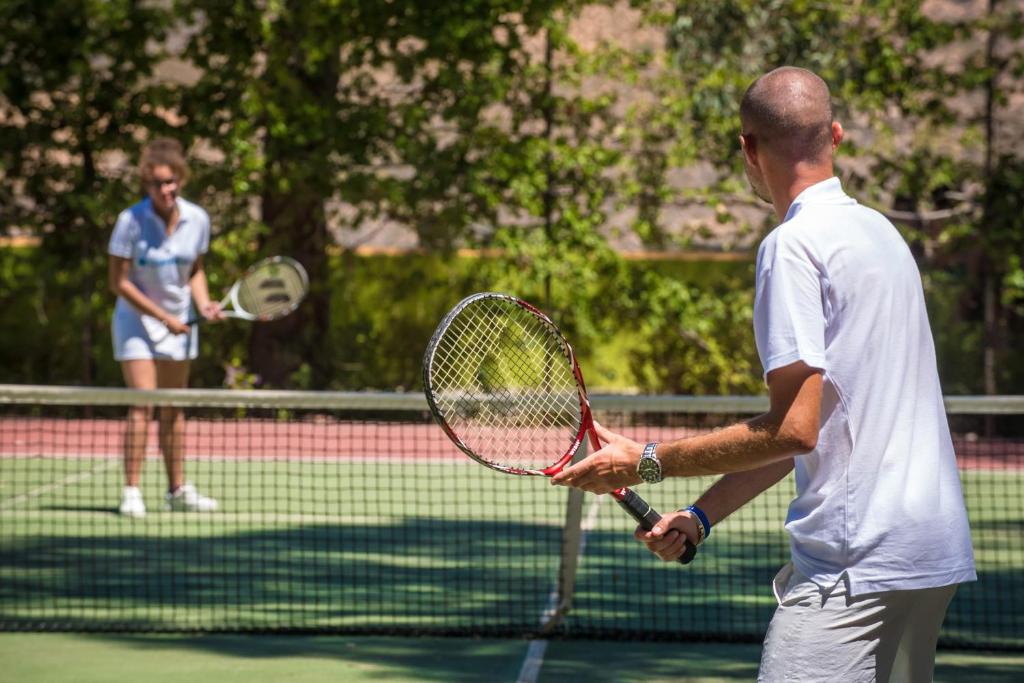 Tennisistu treniņš uz laukuma, kur viens spēlētājs gatavojas izsist bumbu, bet otrs to sagaida.