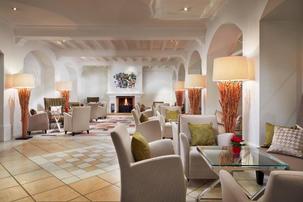 Mūsdienīgs un elegants viesnīcas atpūtas telpas interjers ar ērtām mēbelēm, siltu apgaismojumu un mājīgu kamīnu, kas rada relaksējošu atmosfēru.