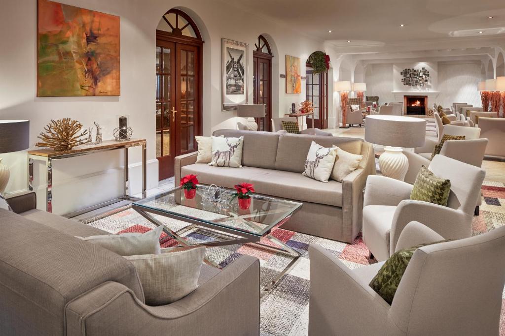 Mūsdienīga viesnīcas uzgaidāmā telpa ar elegantiem dīvāniem, stikla galdu un mākslas darbiem uz sienām, radot komfortablu un stilīgu atmosfēru.