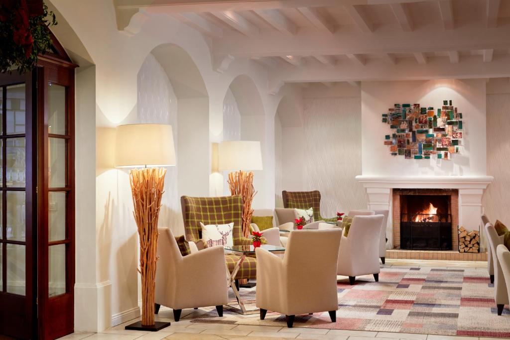 Mūsdienīgs viesnīcas interjers ar ērtām atpūtas zonām, kamīnu un dekoratīvām lampām, radot siltu un viesmīlīgu atmosfēru.