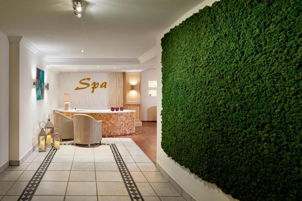Mūsdienīgs spa interjers ar zaļo sūnu sienu un elegantu uzņemšanas zonu, kas rada relaksējošu atmosfēru. Iekārtots ar ērtām mēbelēm un siltām gaismām.