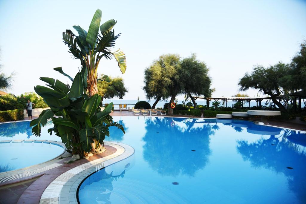 Lielisks baseins ar palmām un zaļumiem, kas atspoguļojas ūdenī, piedāvā relaksējošu atmosfēru pie jūras. Ideāla vieta atpūtai un baudīšanai.