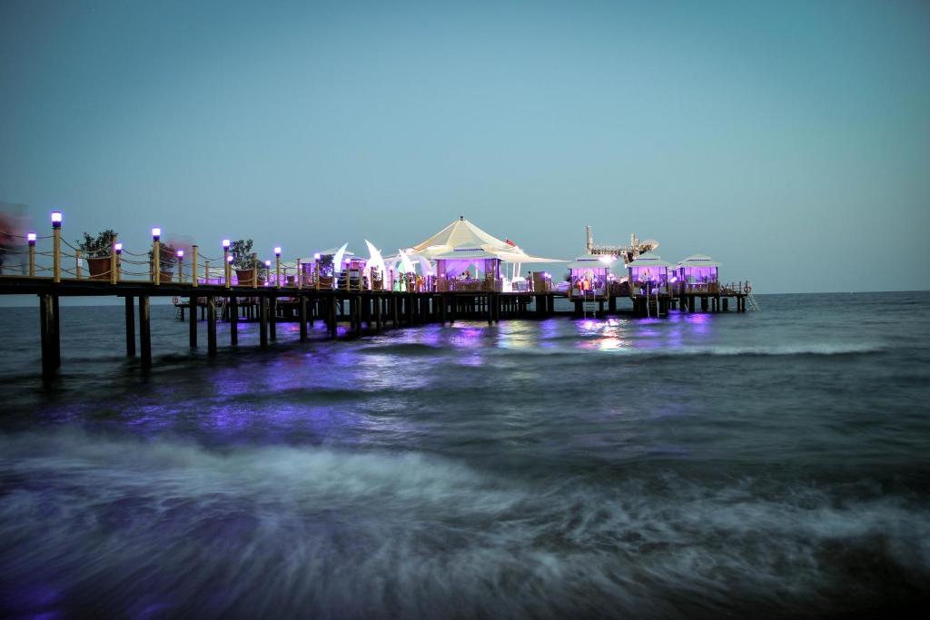 Piestātnes ainava ar apgaismotām konstrukcijām un jūras viļņiem, radot relaksējošu atmosfēru. Ideāla vieta vakara atpūtai un izklaidei.