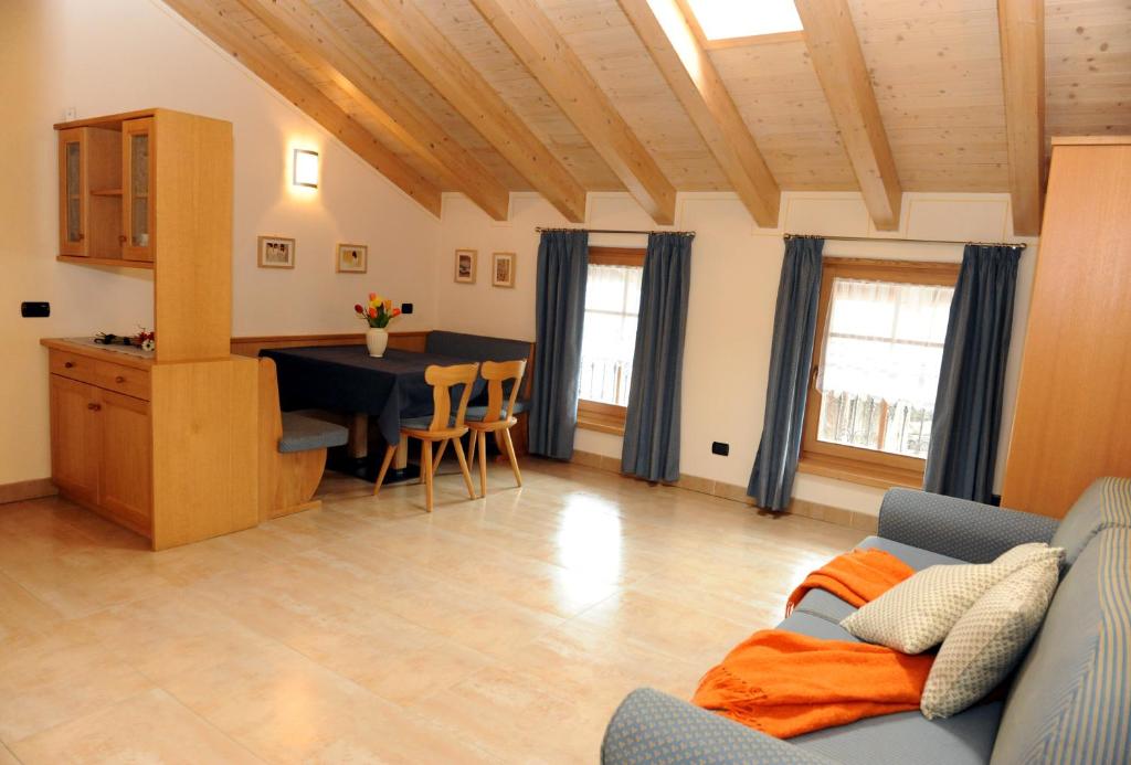 Mūsdienīga un gaiša viesistaba ar koka griestiem, ēdamgaldu un dīvānu, kas dekorēts ar spilveniem un segu. Logi ar tumši zilu aizkaru nodrošina dabisko apgaismojumu un mājīgu atmosfēru.