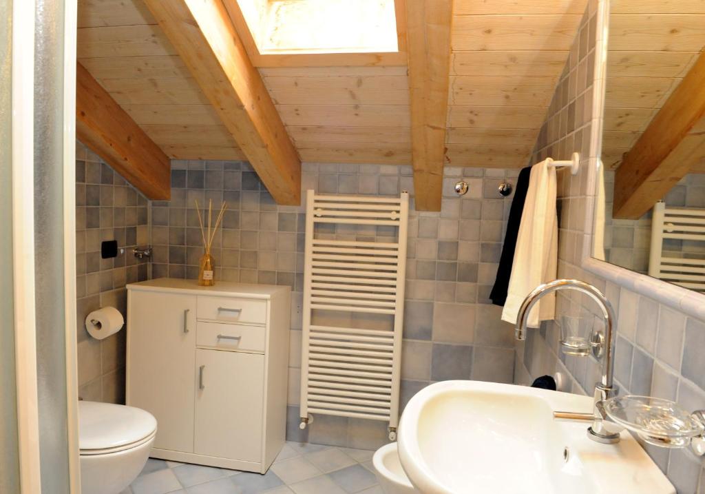 Moderns vannas istabas interjers ar koka sijām un flīzēm, ietverot tualeti, izlietni un radiatoru. Gaismas avots no jumta loga piešķir telpai gaišumu.