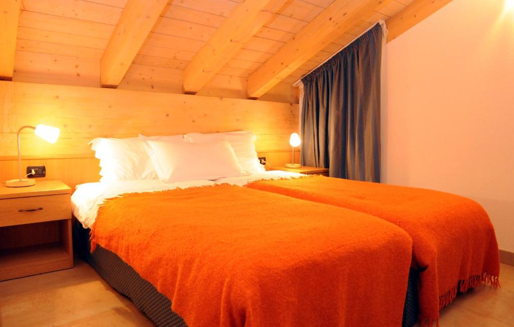 Siltā un mājīgā guļamistaba ar divām atsevišķām gultām, pārklātām ar oranžām sega, un koka siju griestiem. Galds ar lampu un aizkaru logs papildina telpas komfortu.