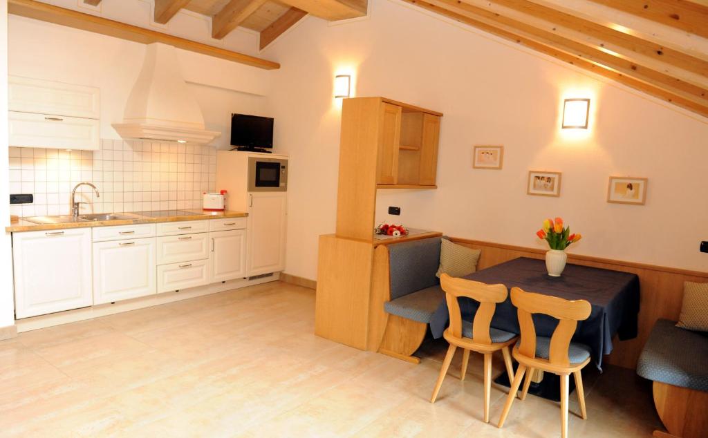 Gaiša un moderna virtuve ar koka griestiem, aprīkota ar mūsdienīgu tehniku, ieskaitot mikroviļņu krāsni un galdu ar ziediem. Eleganta dizaina interjers rada mājīgu atmosfēru.