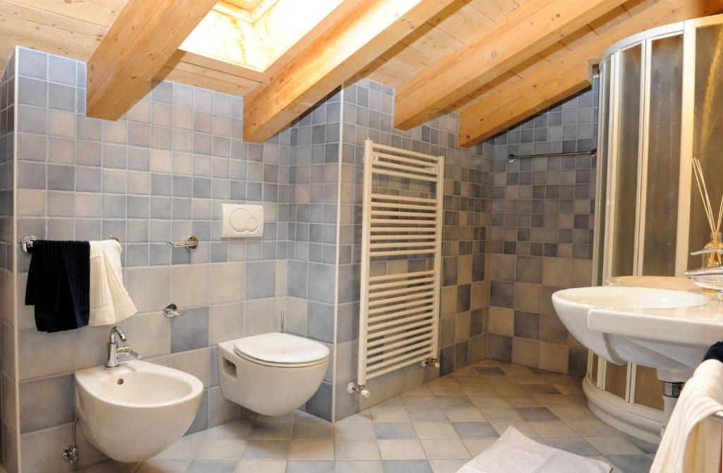 Moderns vannas istabas interjers ar koka sijas, pelēkā flīzēta grīda un sienas, dušas kabīne un sanitārtehnika. Elegants un funkcionāls dizains.