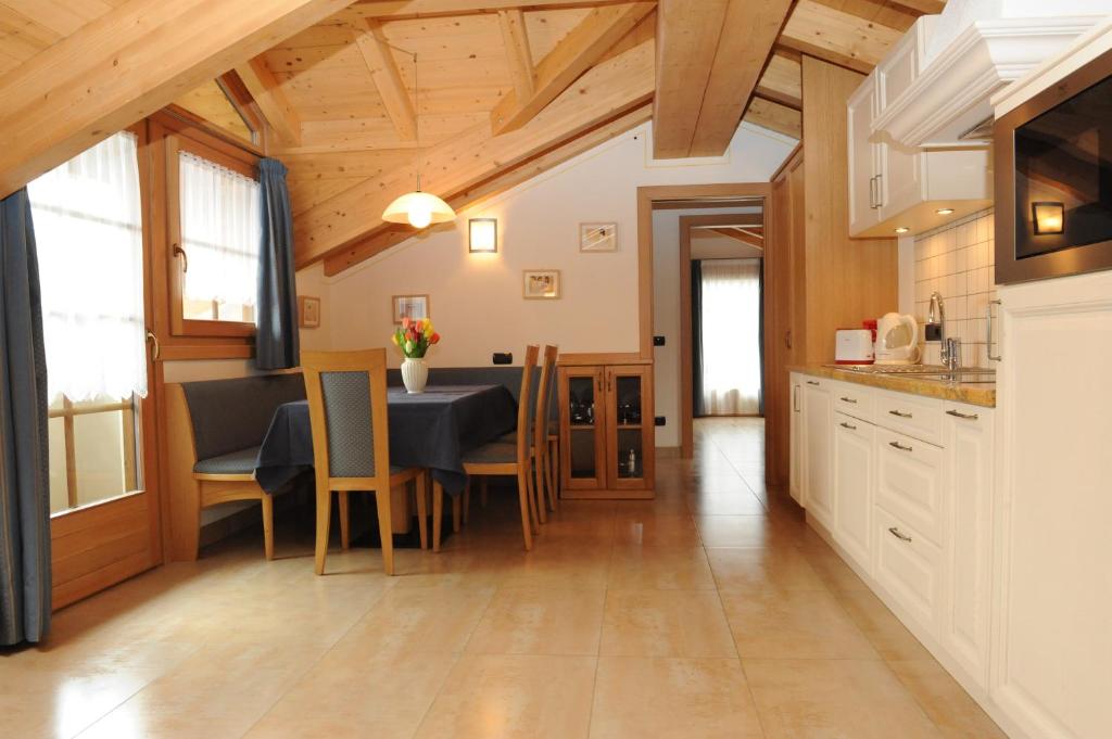 Mājas virtuve ar koka grīdu un griestiem, ēdamzonu ar galdu un krēsliem, kā arī mūsdienīgu virtuves iekārtu. Gaisma ienāk caur logiem ar aizkariem, radot mājīgu atmosfēru.