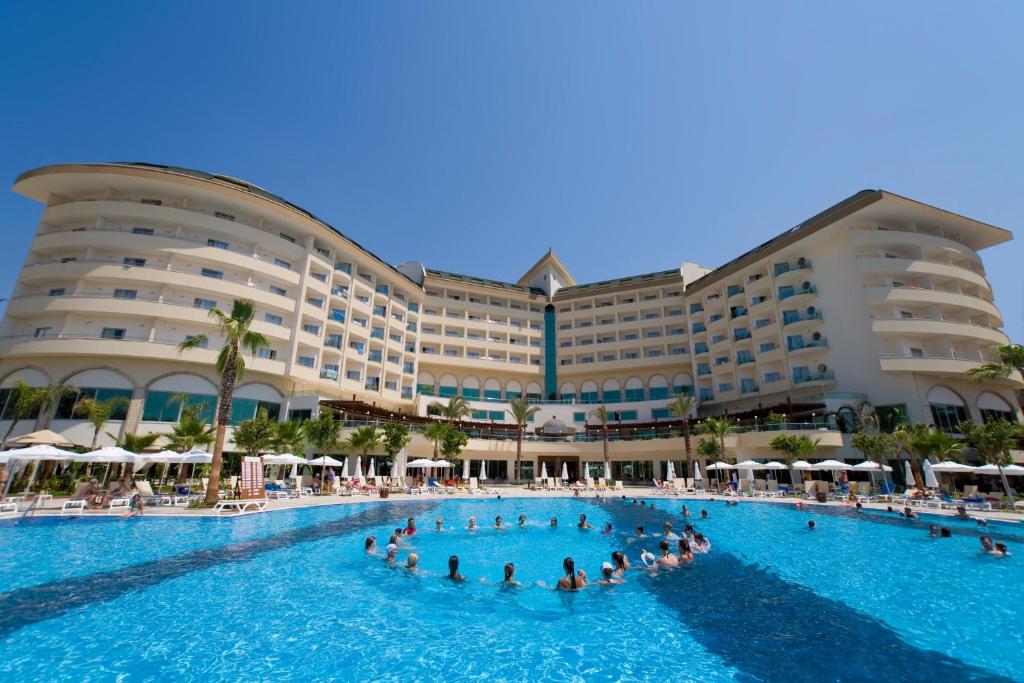 Saphir Resort & Spa viesnīca ar baseinu un apmeklētājiem piekrastē.