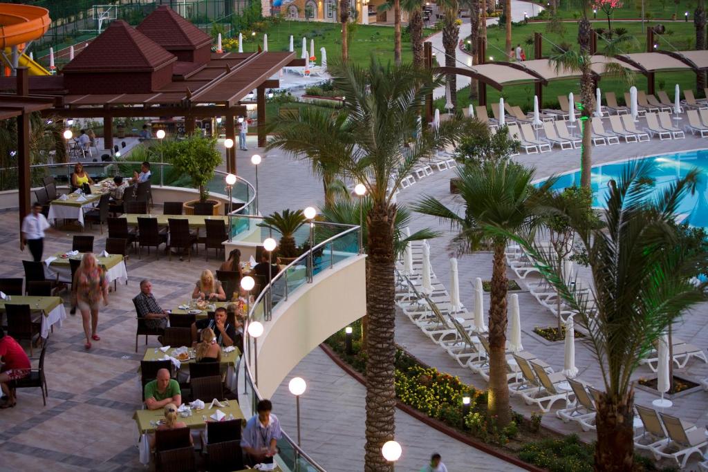 Saphir Resort & Spa terase ar baseinu un palmām, viesi baudot vakariņas.