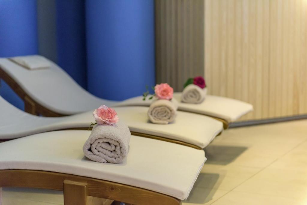 Spa atpūtas zona ar relaksējošām gultām, uz kurām novietoti dvieļi un ziedi. Ideāla vide atpūtai un relaksācijai.