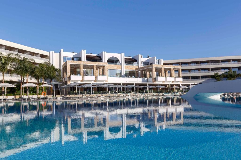 Princess Andriana Resort & Spa piekrastes peldbaseins ar viesnīcas ēku fonā