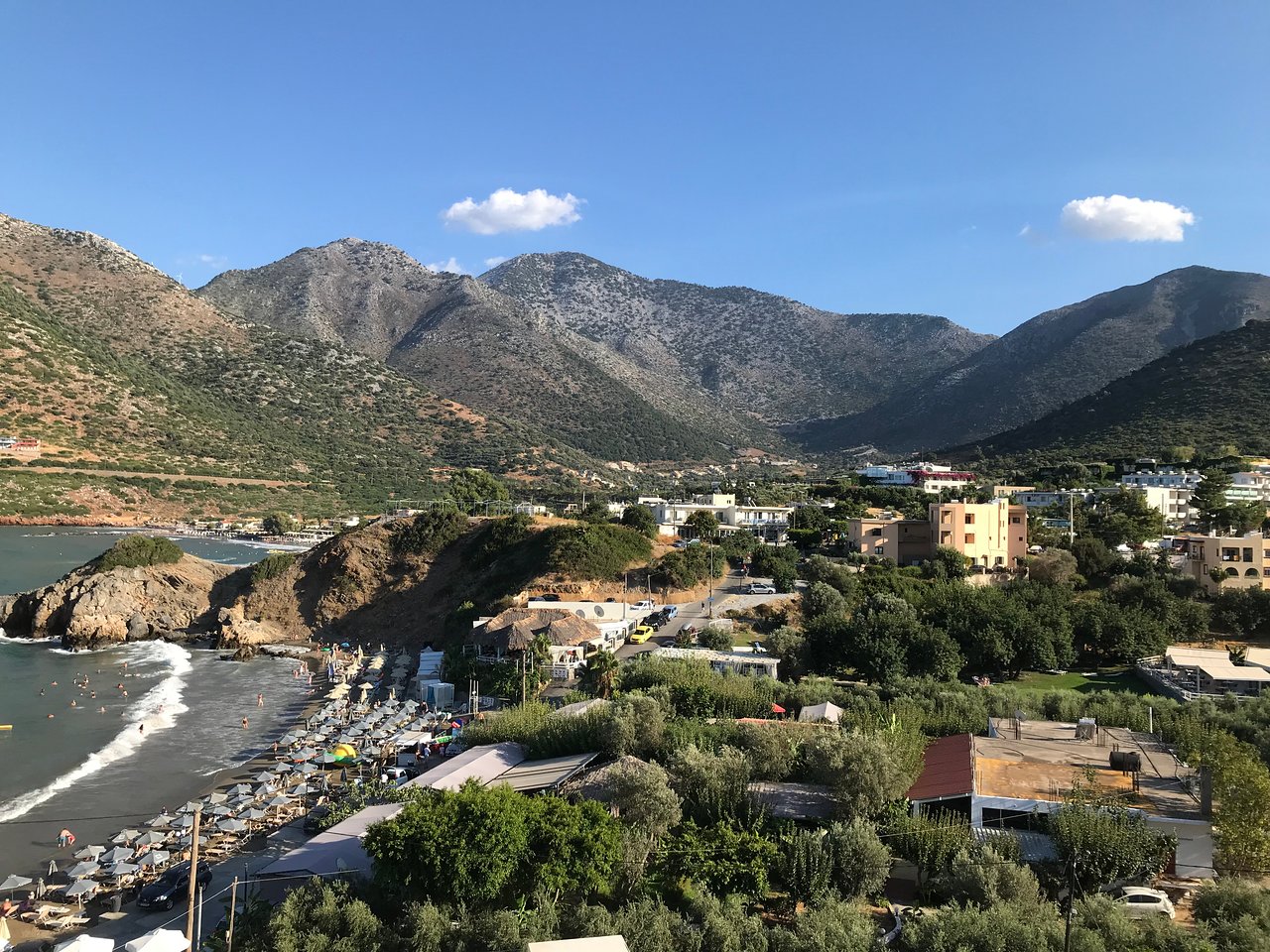Skaists kalnu un piekrastes skats ar pludmali un vasaras aktivitātēm. Zaļš apvidus apvienojas ar kalnu ainavām un zilo debesu fonu. panoramic view with beach and pools
