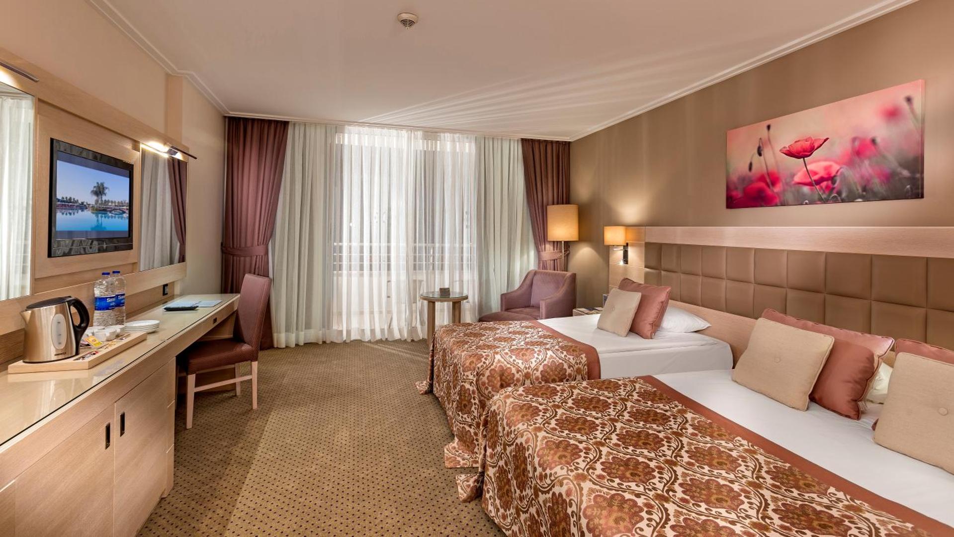 Miracle Resort Hotel gaišs standarta numurs ar divām gultām, rakstāmgaldu un TV Antalijas piekrastē, Turcijā.