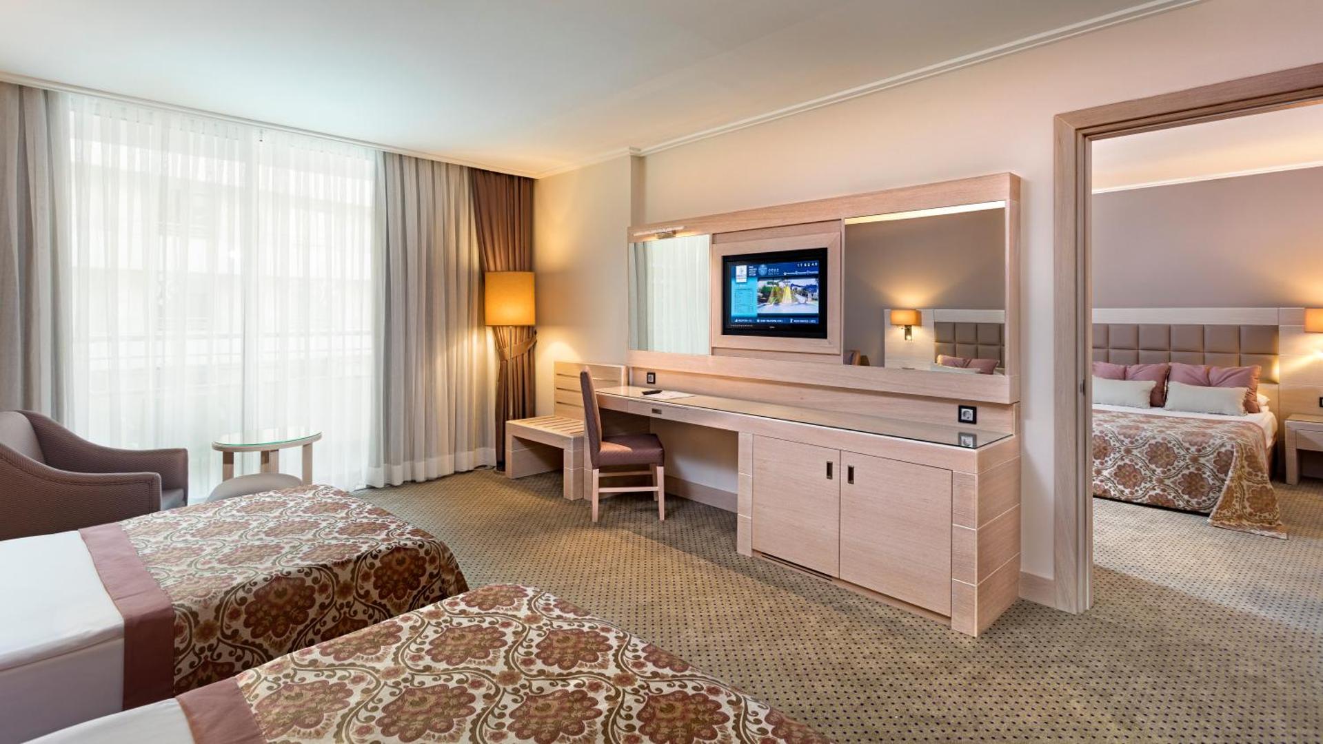 Miracle Resort Hotel plašs ģimenes numurs ar divām telpām, darba zonu un lieliem logiem Antalijā.