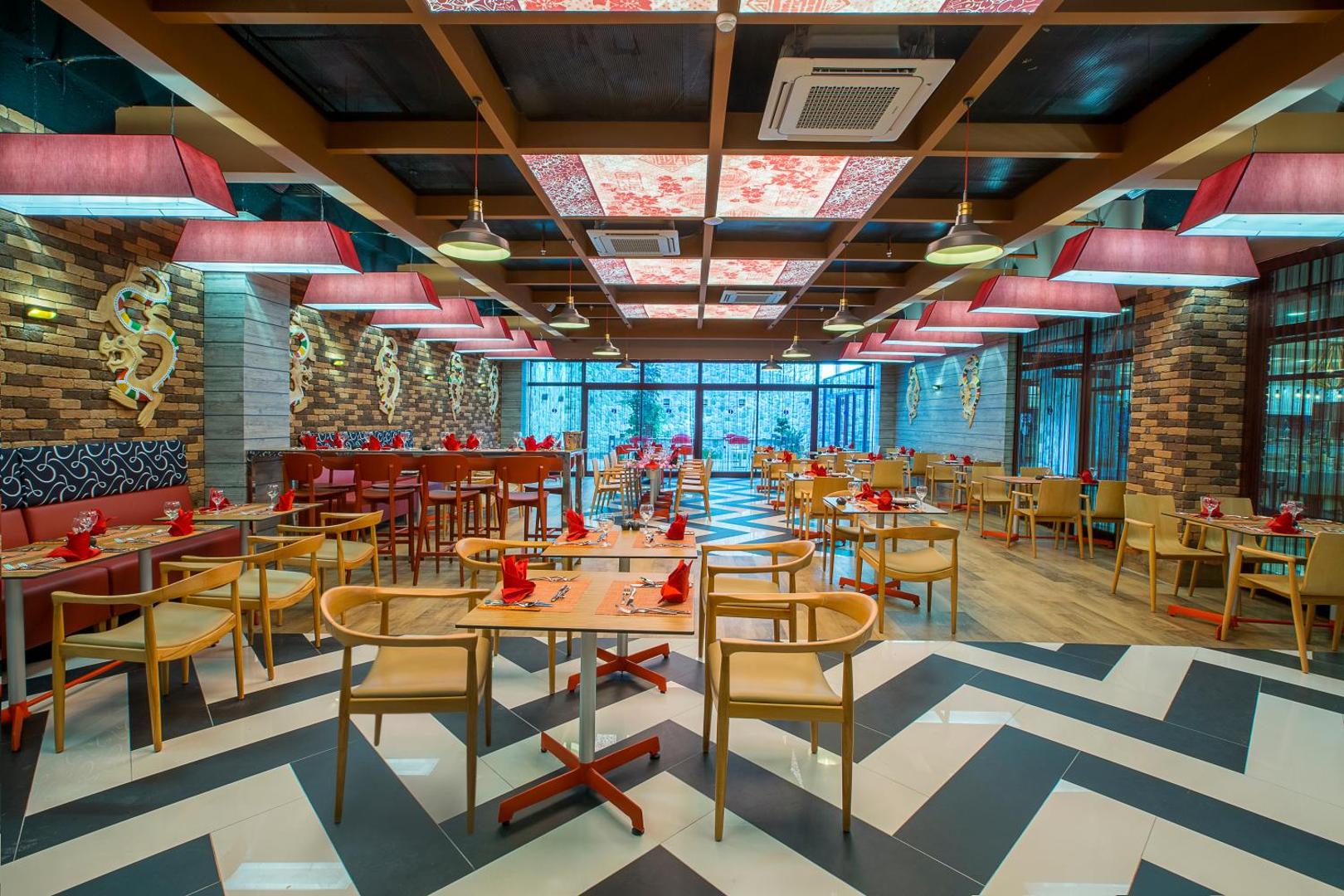 Numa Bay Exclusive Hotel tematiskais restorāns ar modernu interjeru, sarkanām salvetēm un stilīgu apgaismojumu
