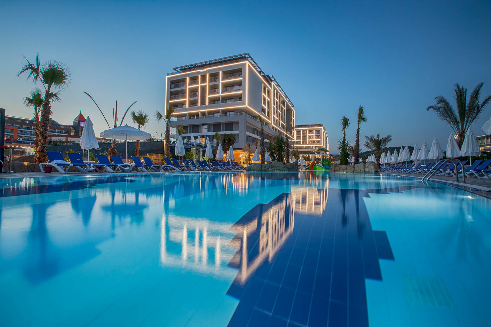 Numa Bay Exclusive Hotel galvenā ēka vakarā ar izgaismotu fasādi un lielu āra baseinu Alānijas reģionā, Turcijā