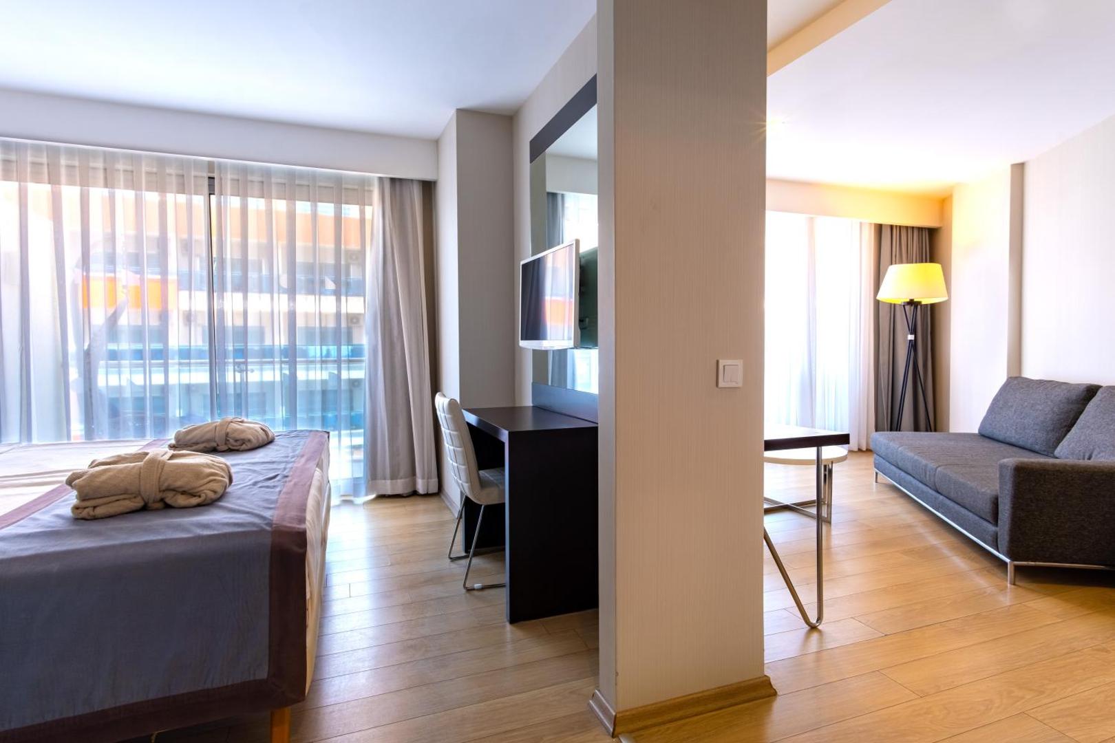 Plašs Selene Beach and Spa Hotel numura interjers ar atpūtas zonu, dīvānu, darba galdu un gaišu koka grīdu
