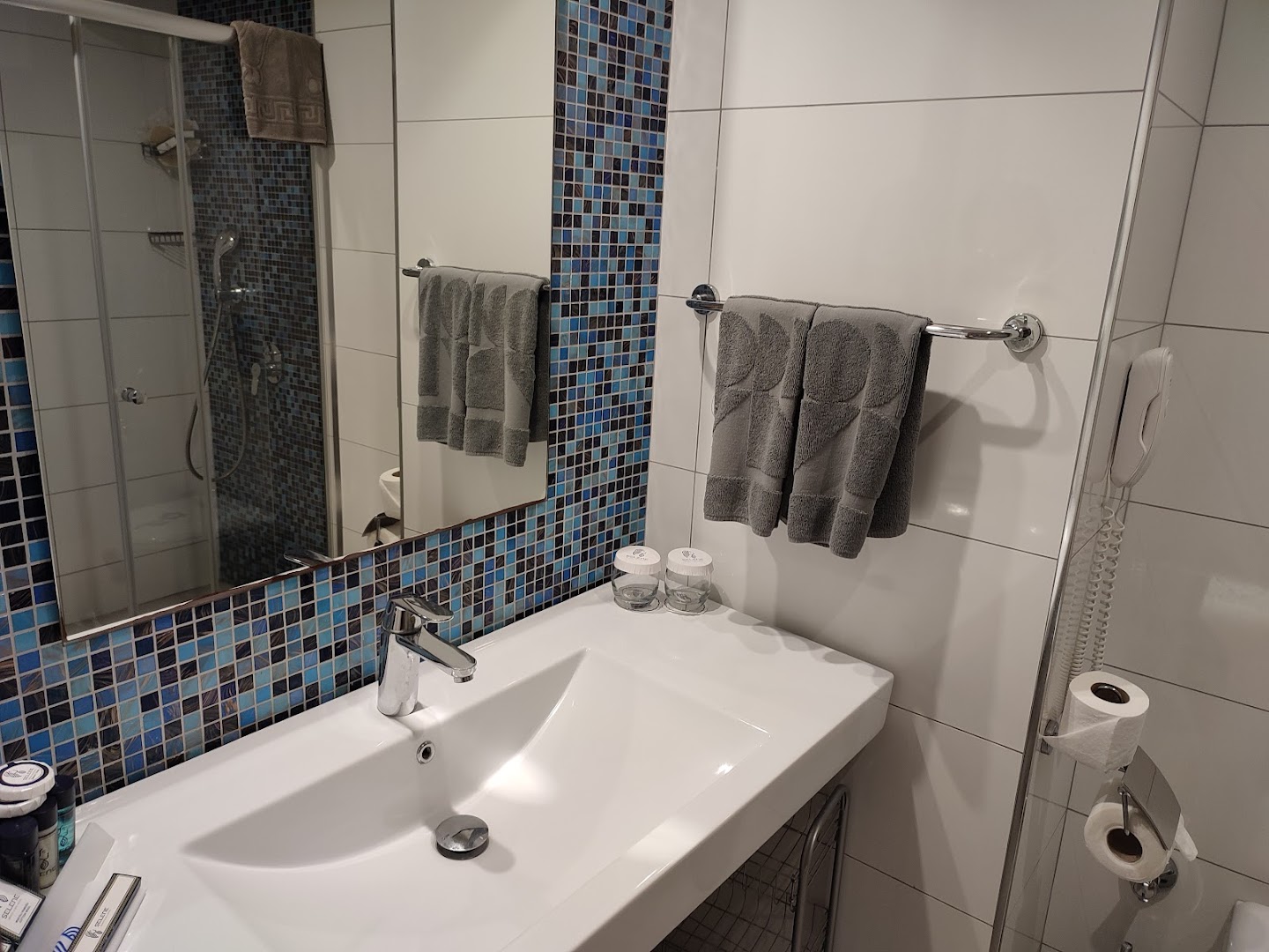 Tuvplāns Selene Beach and Spa Hotel vannas istabas izlietnei ar spoguli, dvieļiem un zilām dekoratīvajām mozaīkas flīzēm