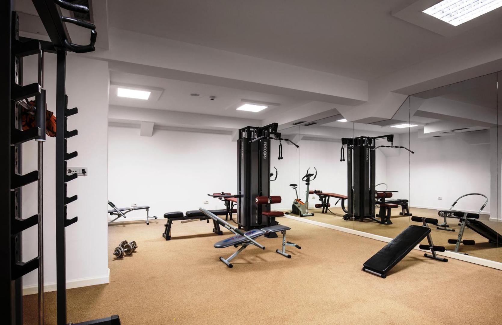Viesnīcas Vile Oliva fitness centrs ar trenažieriem, svariem un spoguļu sienu aktīvai atpūtai Melnkalnes kūrortā.