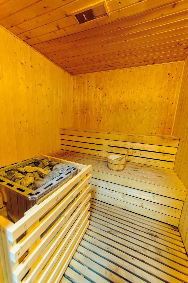Viesnīcas Vile Oliva spa centra koka sauna ar akmens krāsni un koka spaini — relaksācijas zona viesiem Melnkalnē