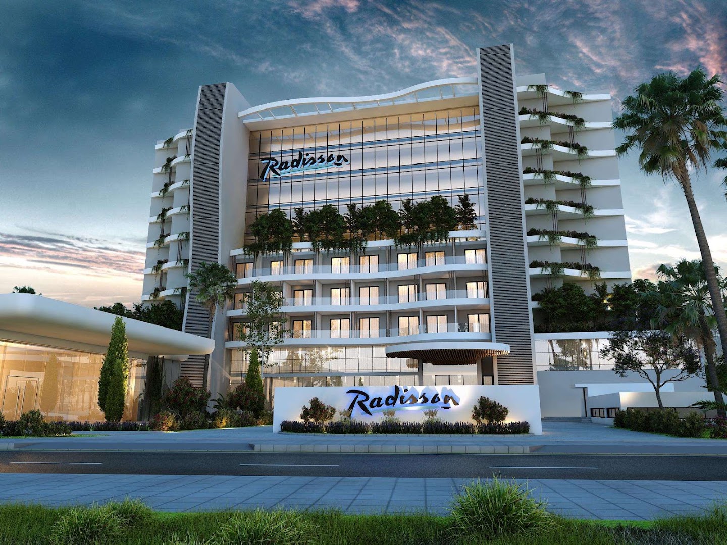 Radisson Beach Resort Larnaca modernā viesnīcas ēka saulrieta laikā Kiprā — arhitektūra ar balkoniem, palmām un izgaismotu logotipu pie ieejas