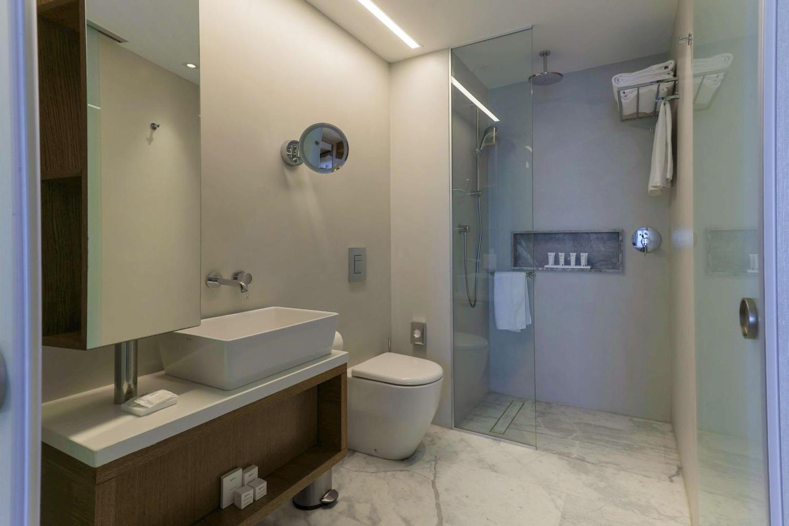 Radisson Beach Resort Larnaca numura vannas istaba ar marmora grīdu, dušas kabīni, modernu izlietni un lielu spoguli
