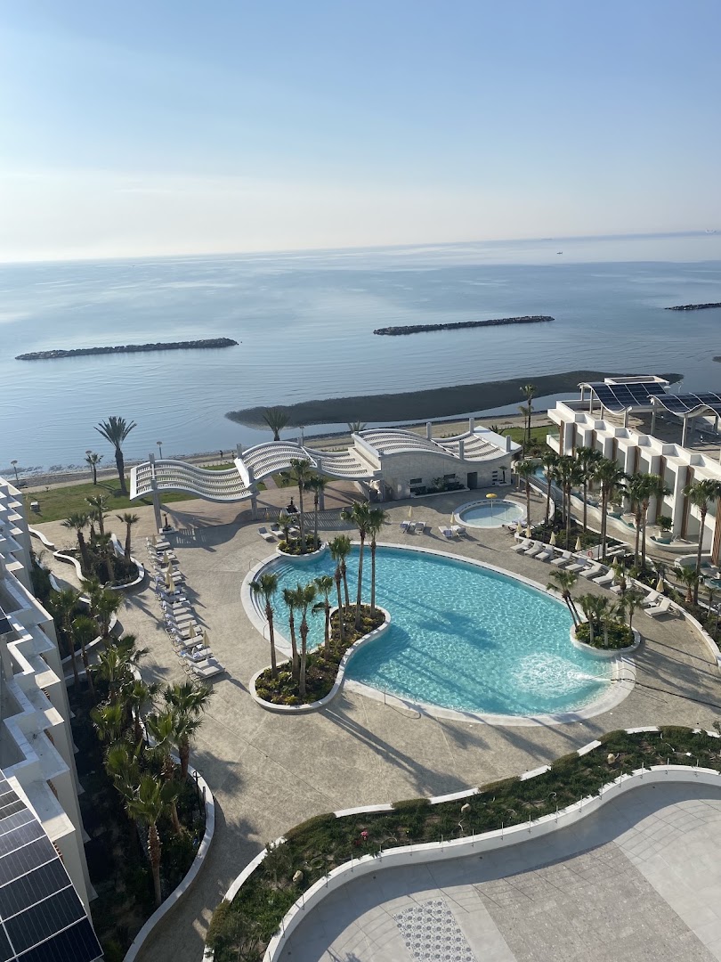 Skats no augšas uz Radisson Beach Resort Larnaca teritoriju, baseinu un Vidusjūras piekrasti ar viļņlaužiem Larnakas reģionā