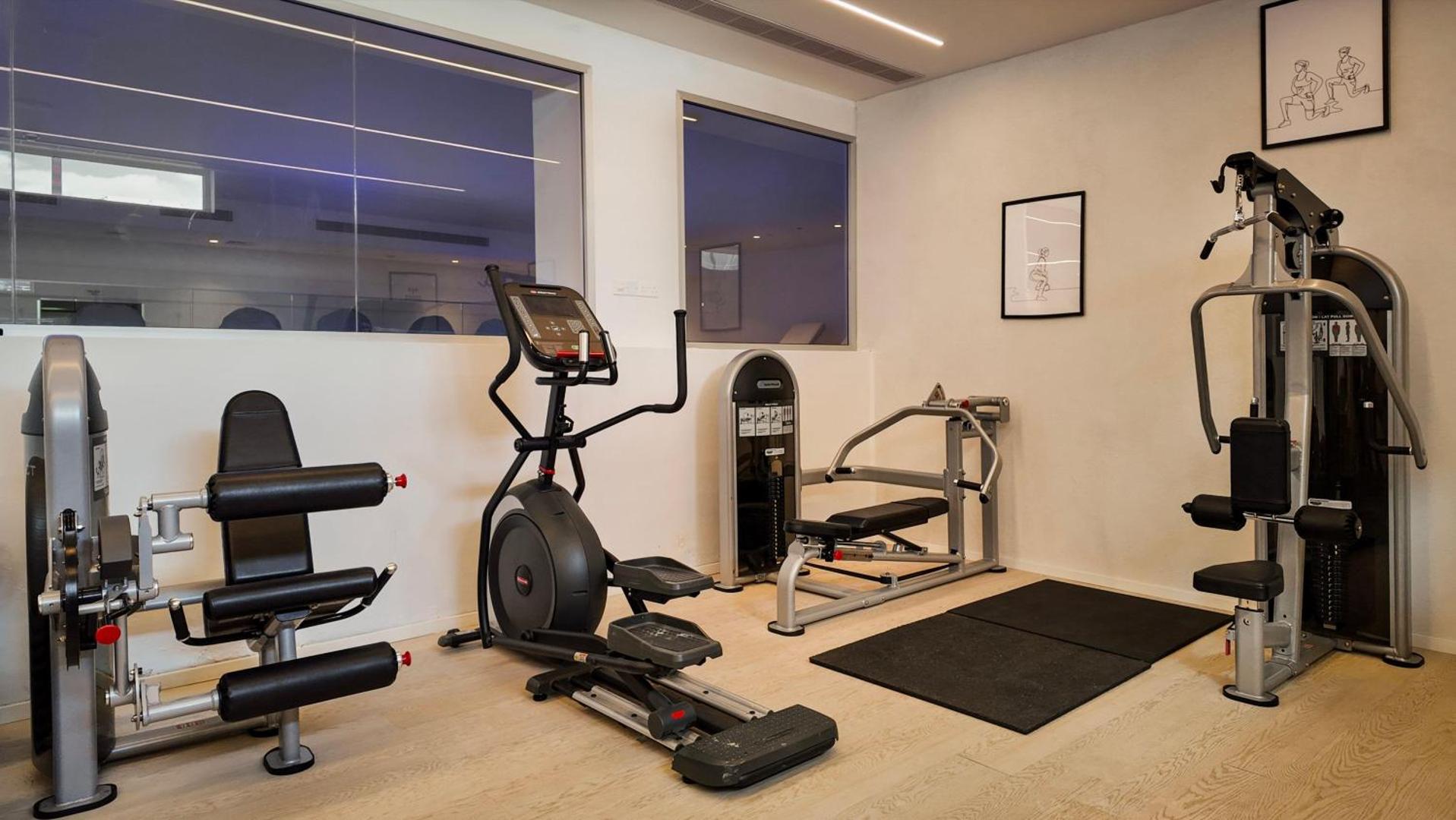 Radisson Beach Resort Larnaca trenažieru zāle ar modernu fitnesa aprīkojumu, eliptisko trenažieri un spēka iekārtām gaišā telpā Kiprā