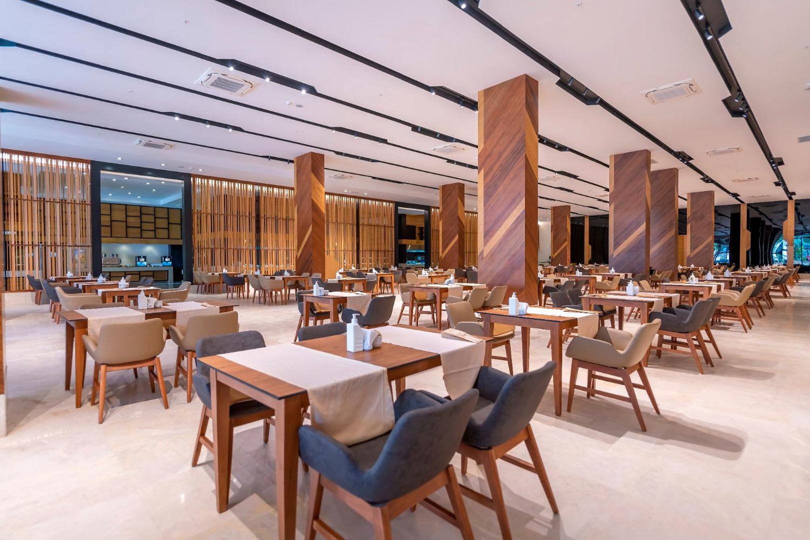 Sorgun Akadia Hotel Luxury galvenais restorāns ar modernu interjeru, koka kolonnām un plašu galdiņu izkārtojumu viesu ērtībām