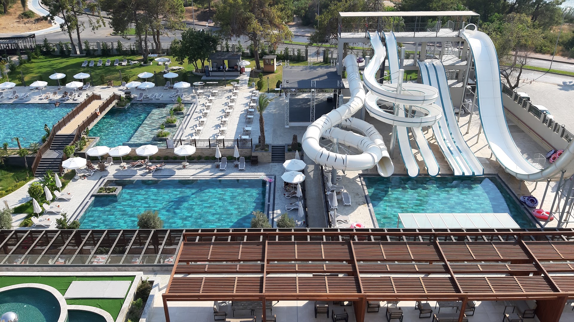 Sorgun Akadia Hotel Luxury akvaparks ar vairākiem ūdens slidkalniņiem un atpūtas zonu no augšas — blakus esošie baseini un sauļošanās terases