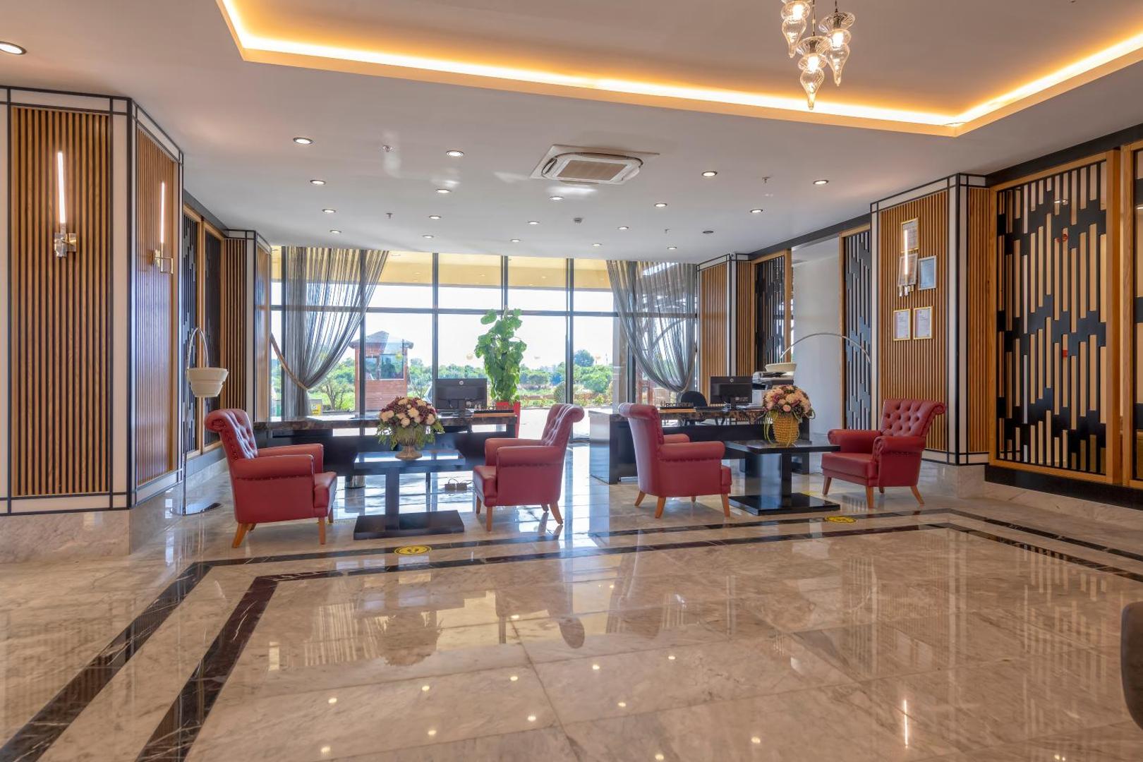 Sorgun Akadia Hotel Luxury recepcijas zona ar sarkanām atpūtas mēbelēm, spīdīgu marmora grīdu un modernu apgaismojumu