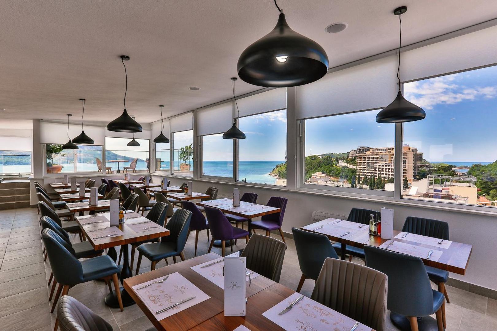Hotel Lusso Mare restorāna zāle ar lieliem panorāmas logiem, no kuriem paveras skats uz jūru un piekrasti