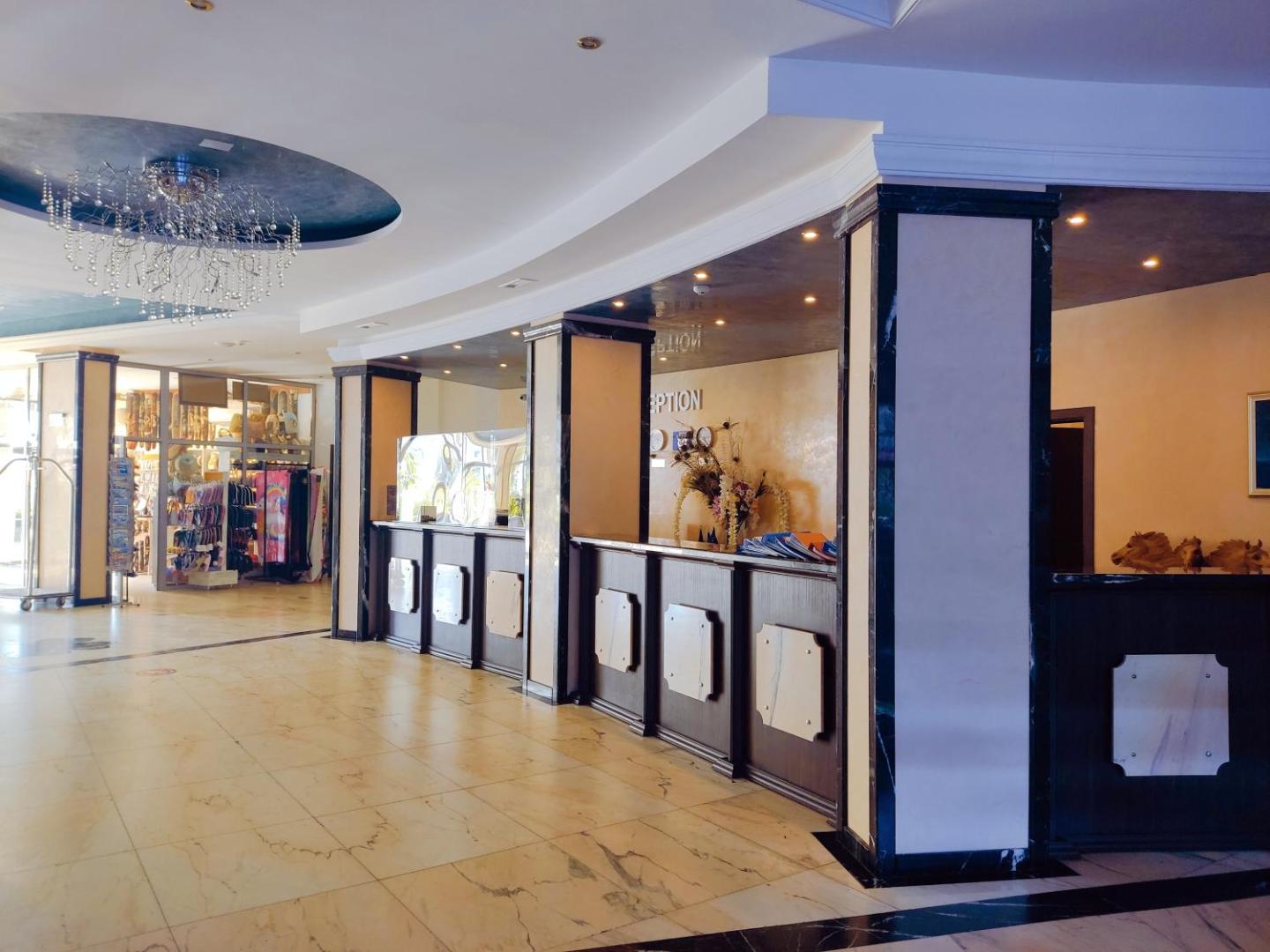 Moonlight Hotel viesnīcas recepcijas zona ar tumša koka leti, marmora grīdu un greznu kristāla lustru pie griestiem