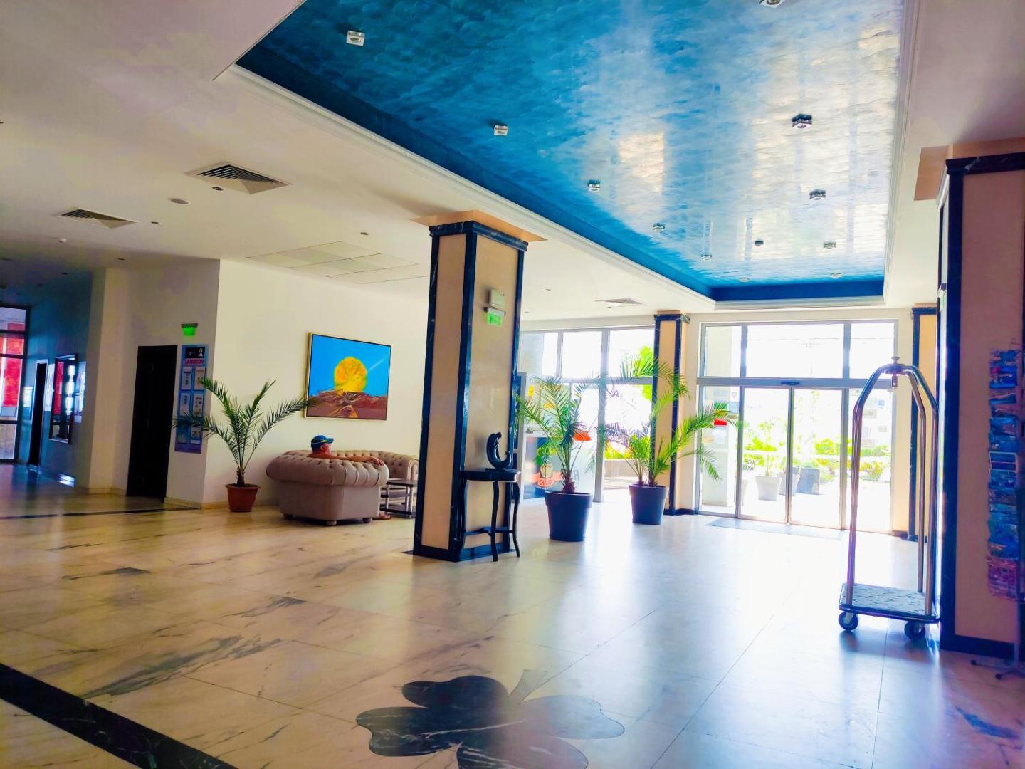 Moonlight Hotel gaišais vestibils ar atpūtas zonu, dīvānu, dekoratīviem augiem un stikla durvīm uz viesnīcas ieeju
