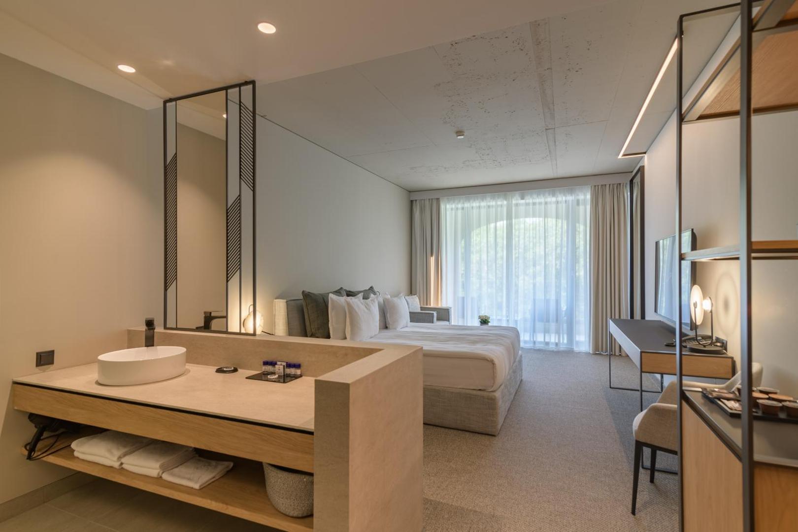 Plašs Aquahouse Hotel & SPA numurs ar atvērtā plānojuma vannas istabas zonu, izlietni un skatu uz guļamzonu un balkonu