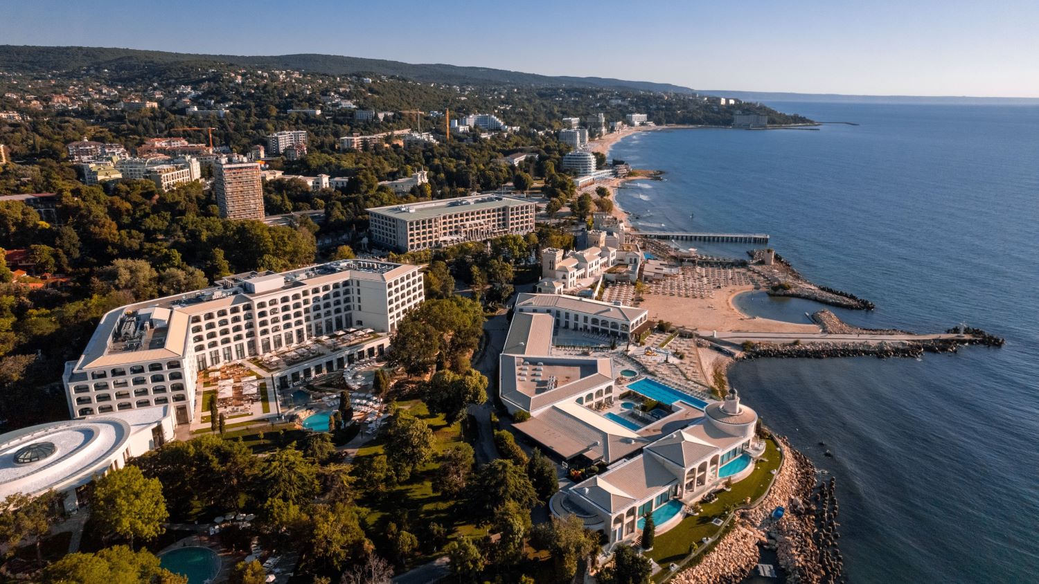 Panorāmas skats uz Aquahouse Hotel & SPA Bulgārijas piekrastē — plaša viesnīcas teritorija ar baseiniem, zaļo zonu un privāto pludmali