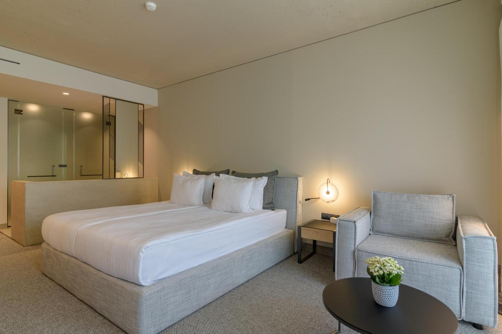 Aquahouse Hotel & SPA moderns numurs ar divguļamo gultu, atpūtas krēslu un minimālistisku dizainu gaišos toņos Bulgārijas kūrortā