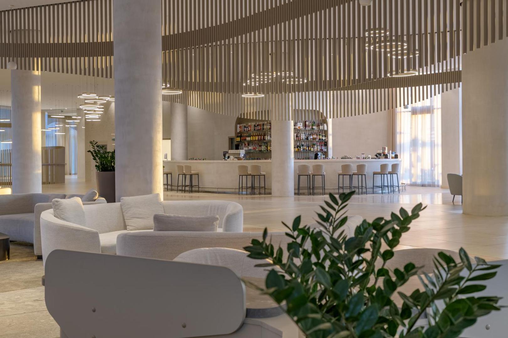 Aquahouse Hotel & SPA lobby bārs ar gaišām mēbelēm, augstiem griestiem un modernu interjera dizainu