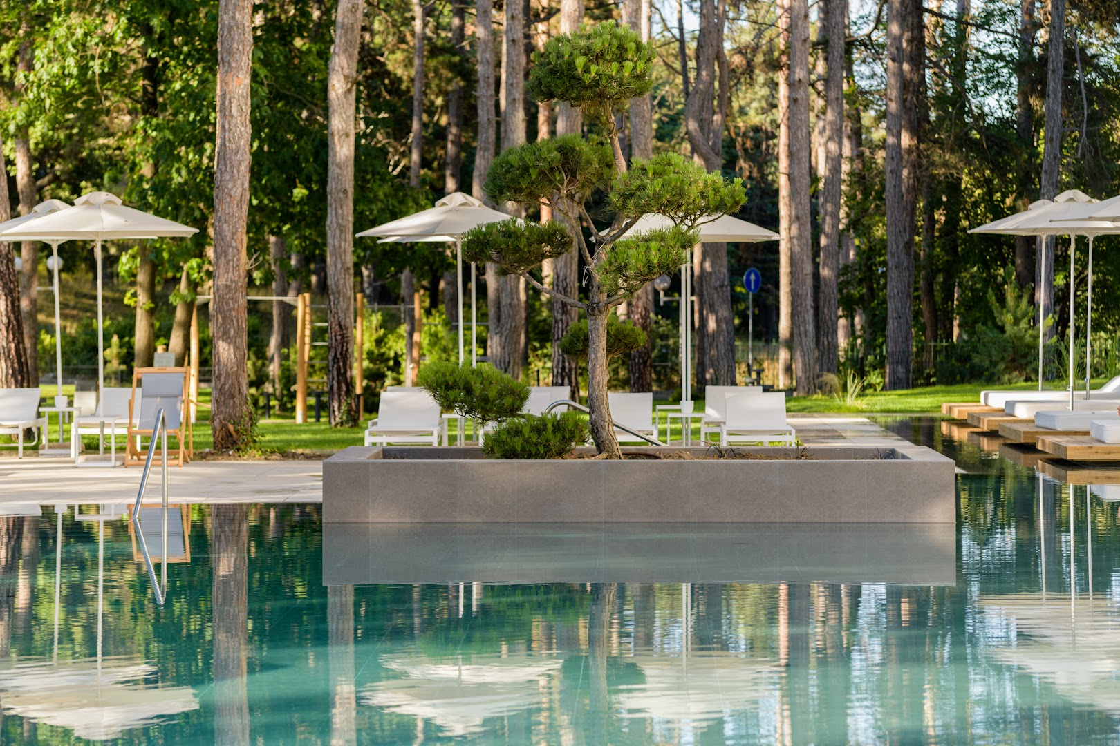 Aquahouse Hotel & SPA āra baseins priežu meža ieskāvumā ar sauļošanās krēsliem un saulessargiem Bulgārijas piekrastē